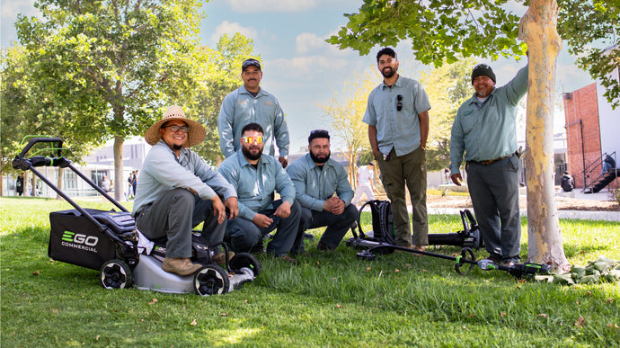 Group of men with EGO lawn mowers in a park setting