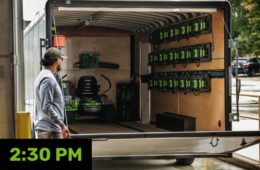 A landscaper opening the back of a van with tools and rows of 56V ARC Lithium™ batteries 